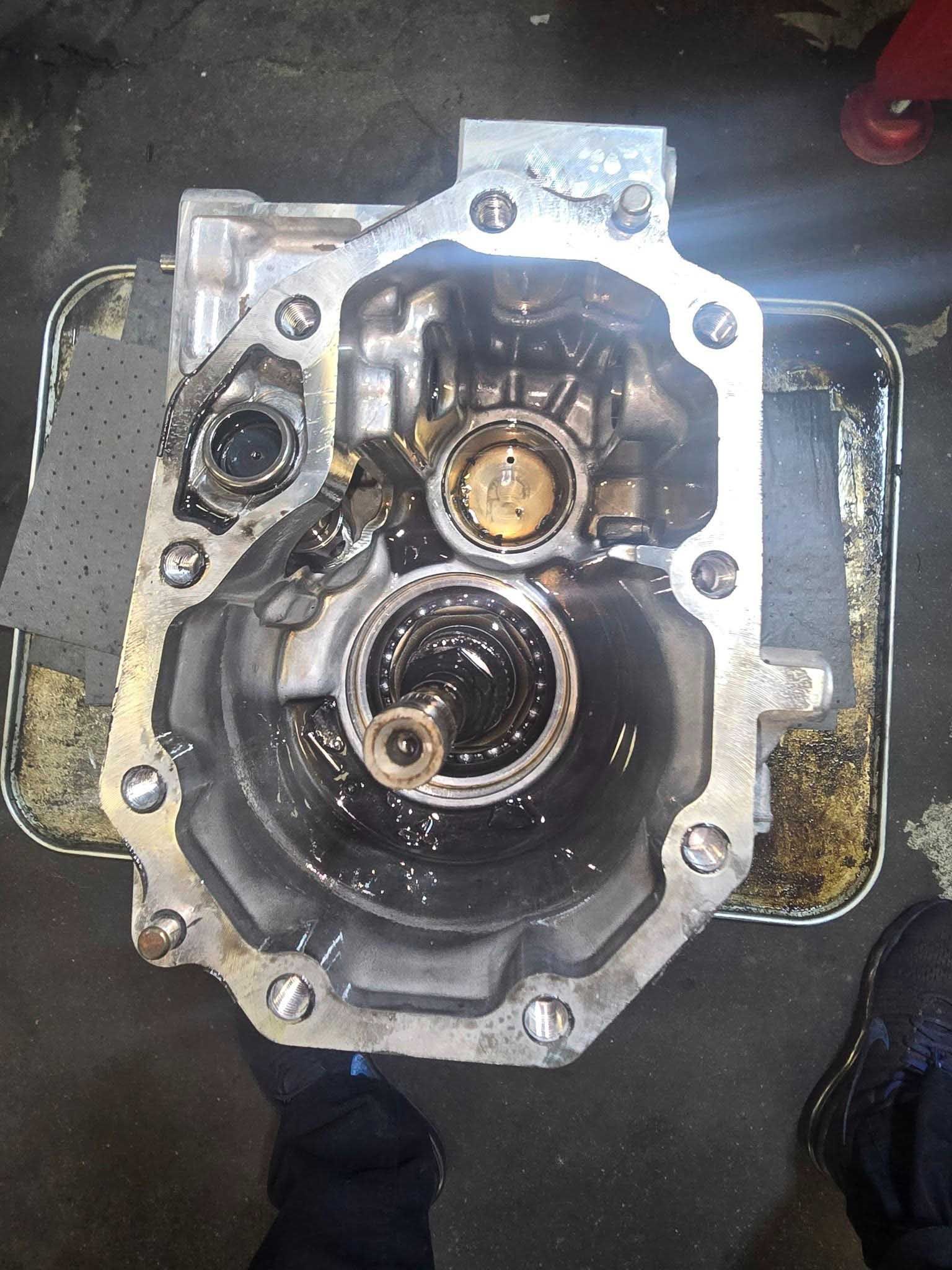 Open car transmission housing, oily, in a metal tray.