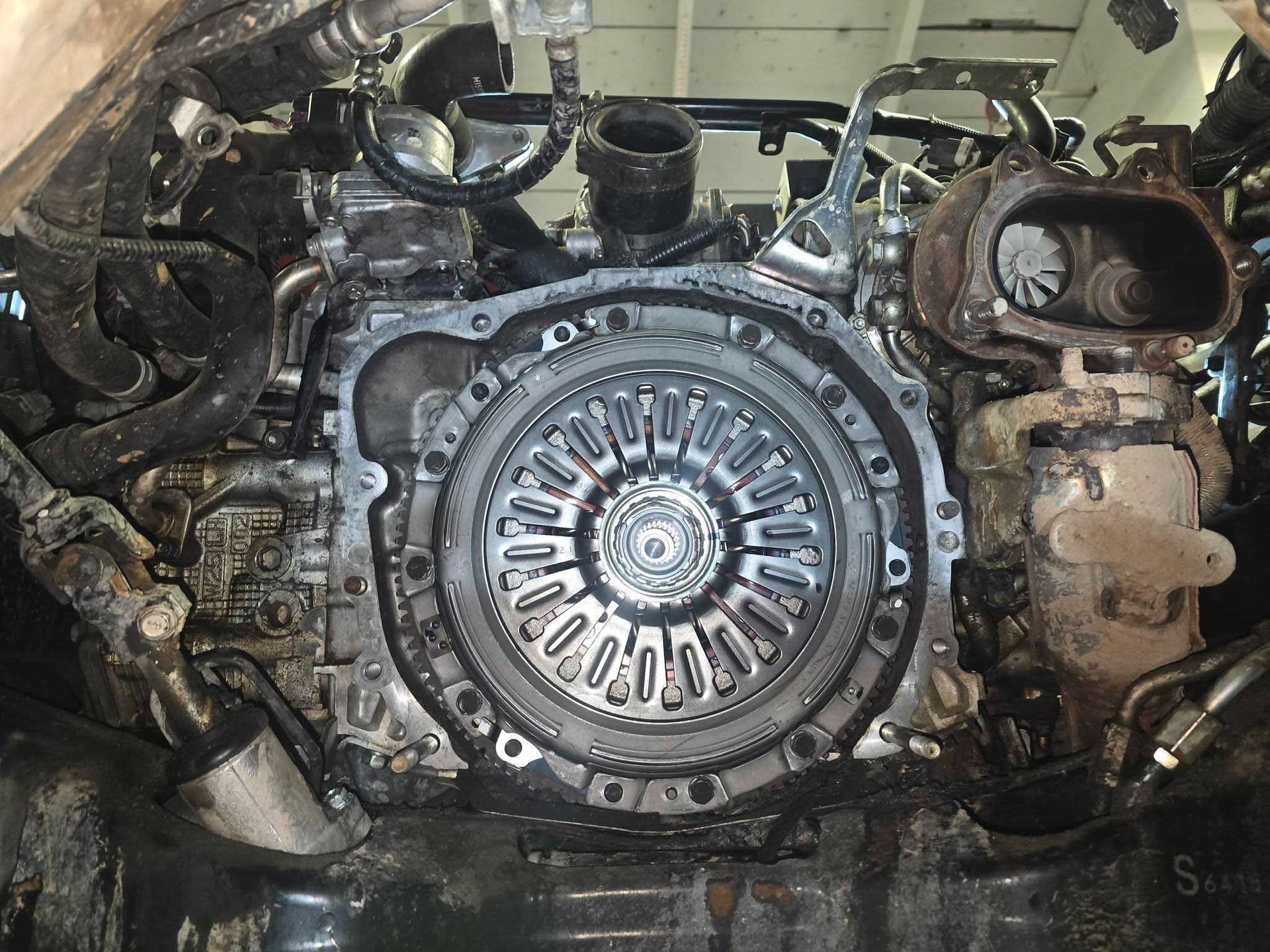 Close-up of a disassembled car engine, revealing the clutch mechanism and surrounding components.