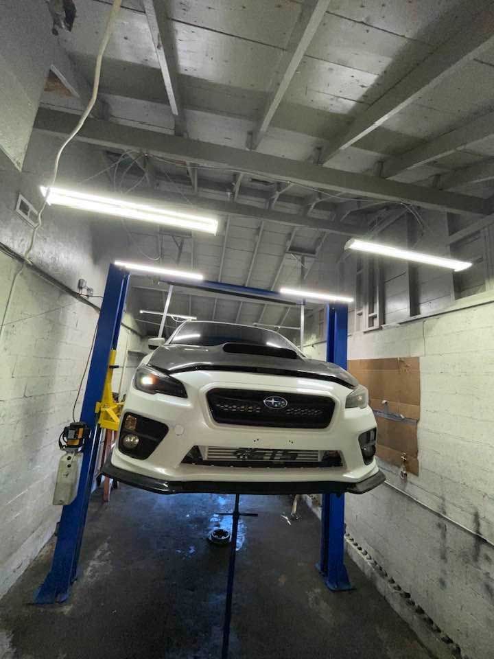 White Subaru WRX on a lift in a garage.