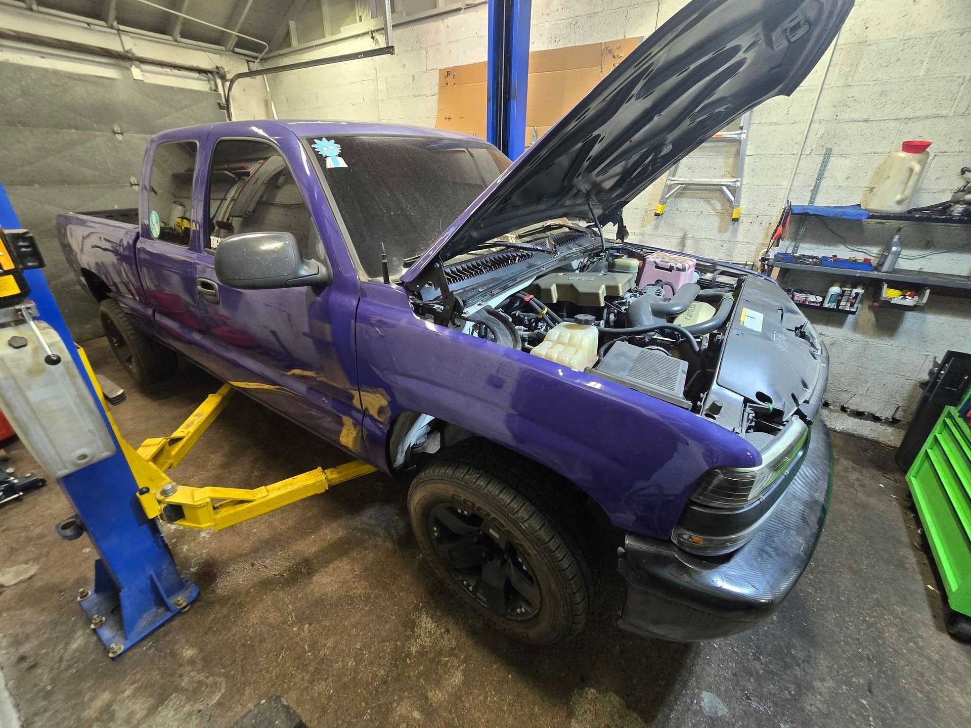 Purple pickup truck with open hood on a lift in a garage.