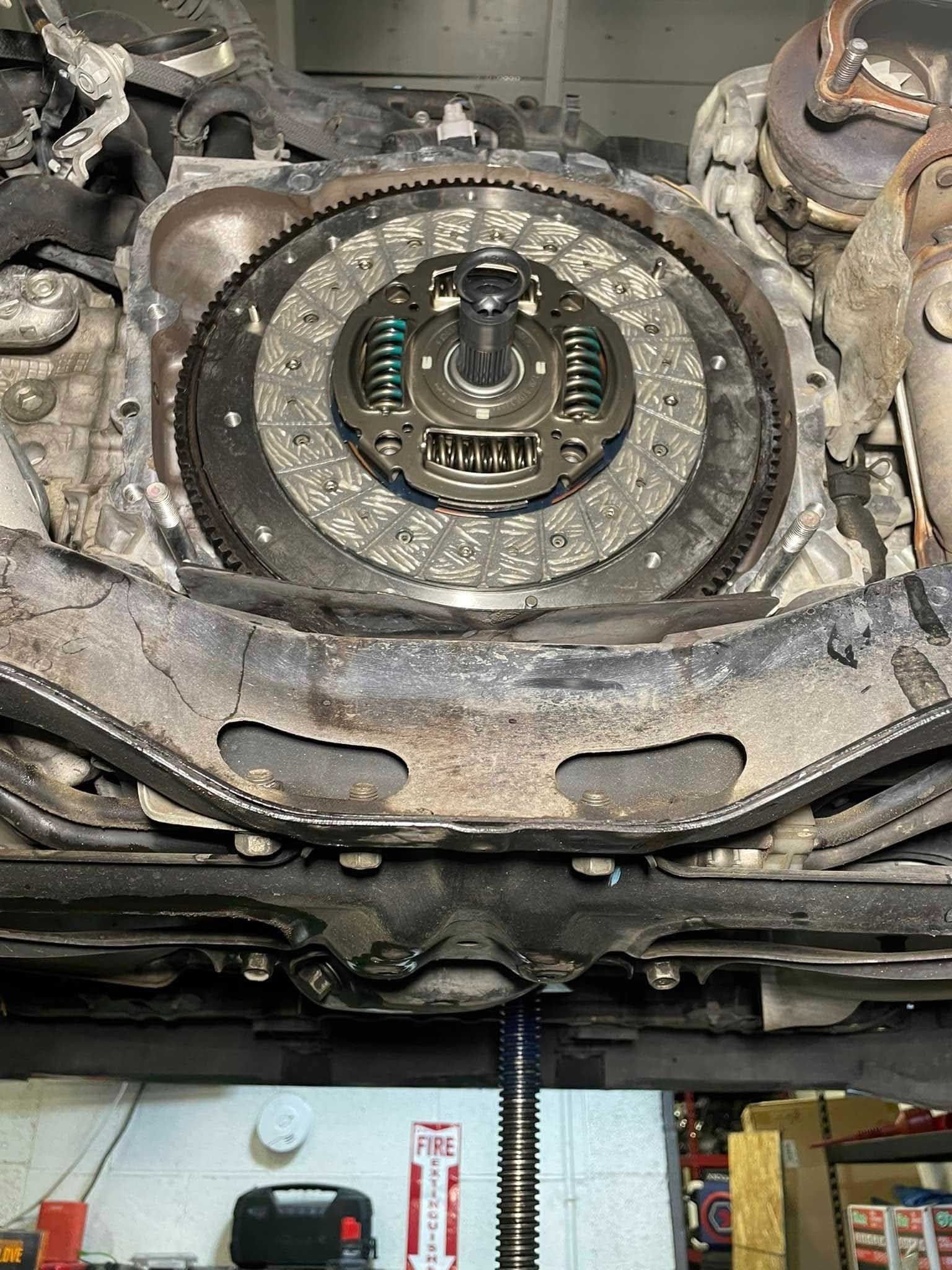 Car transmission with visible clutch assembly and flywheel, viewed from below.