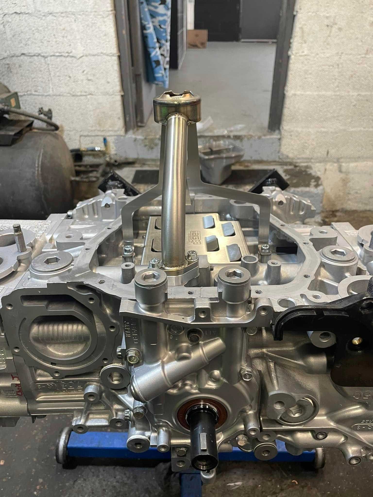 Engine block with a central metal tube and various components, in a workshop setting.