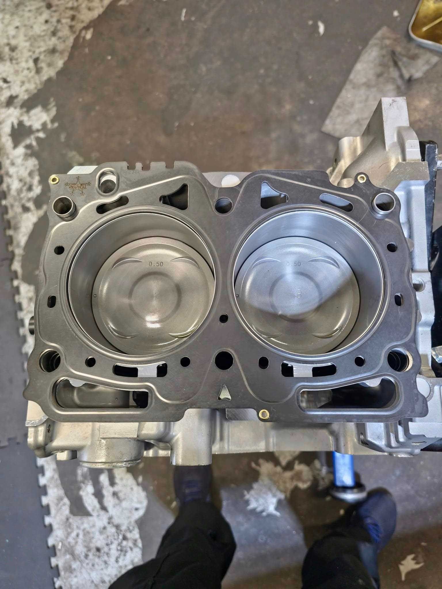 Engine block with pistons visible, head gasket placed on top.