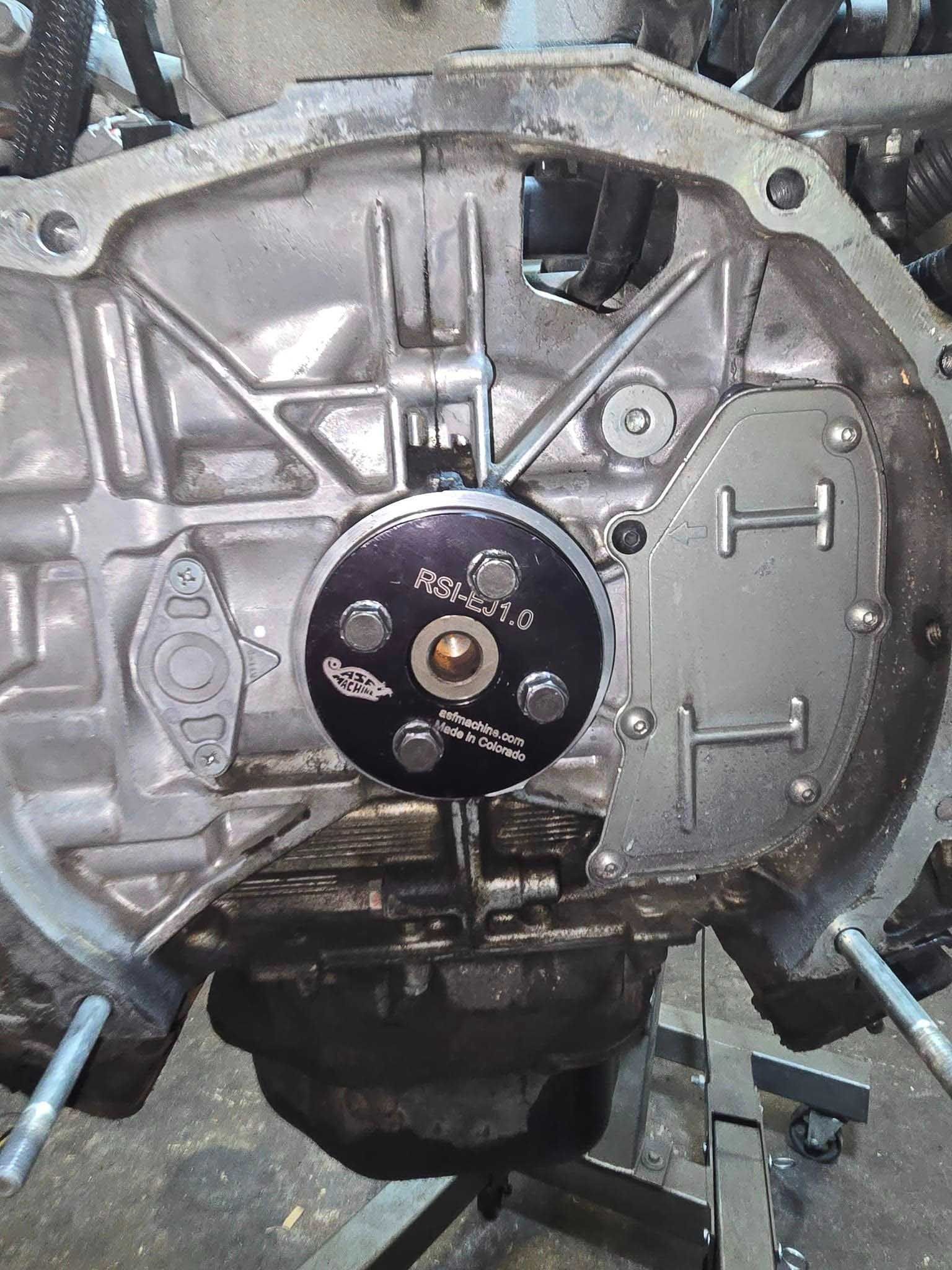 Dial indicator mounted on engine, measuring runout of a flywheel.
