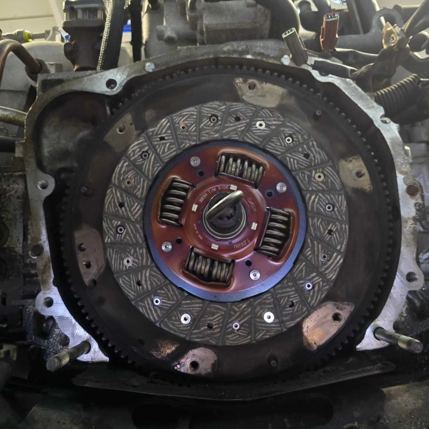 Engine with clutch disc installed, showing metal and reddish-brown components.