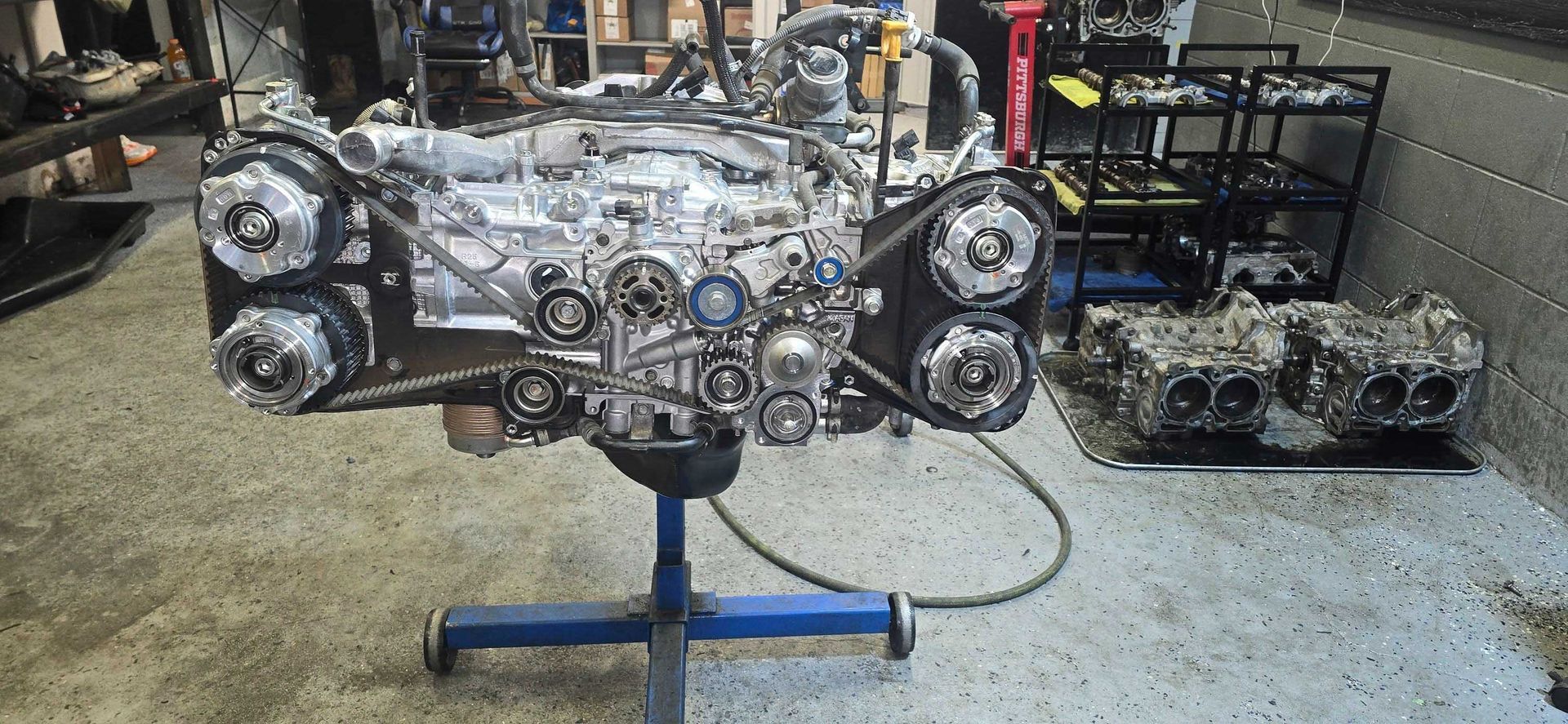 Engine on a stand in a garage, another engine block nearby.