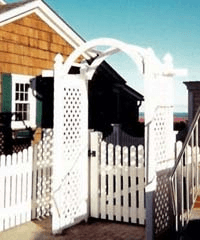 A white fence with a gate in front of a house.