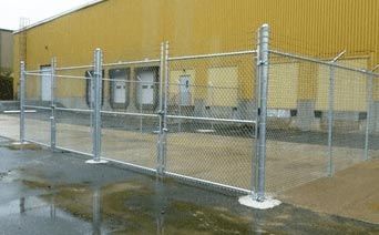 A chain link fence is surrounding a warehouse in front of a building.