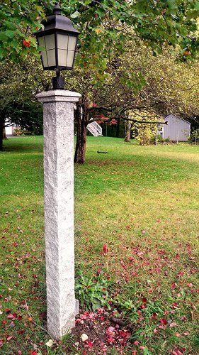 A lamp post in the middle of a lush green field.