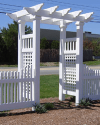 A white pergola with a fence in front of it