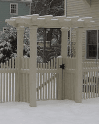 A white fence with a pergola and a gate in the snow