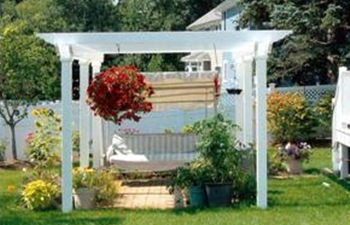 A white pergola is sitting in the middle of a lush green yard.