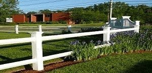 A white fence is in the middle of a lush green field.