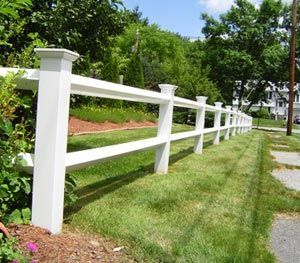 A white fence surrounds a lush green field