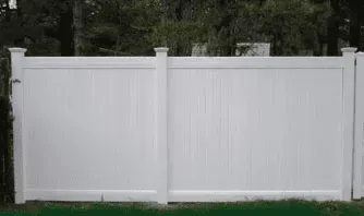 A white vinyl fence is sitting on top of a lush green lawn.