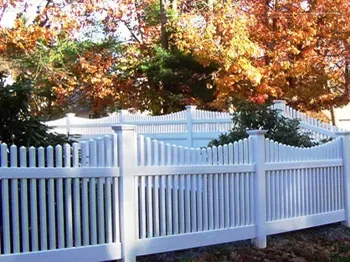 A white picket fence with trees in the background