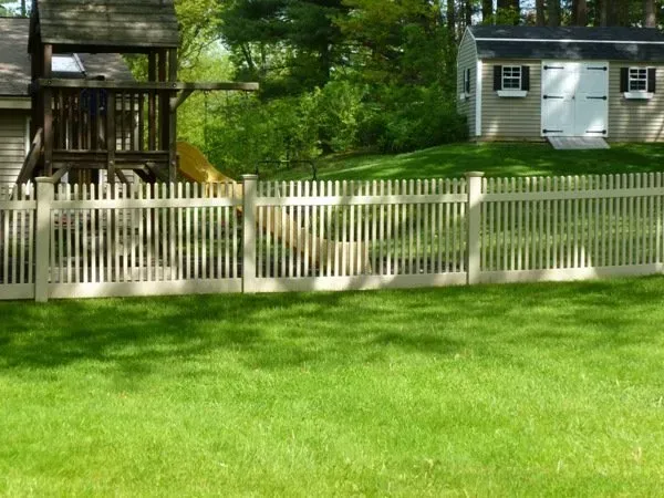 A white picket fence surrounds a lush green yard.