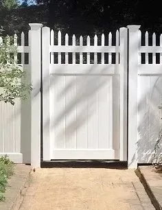 A white fence with a gate in the middle of it.