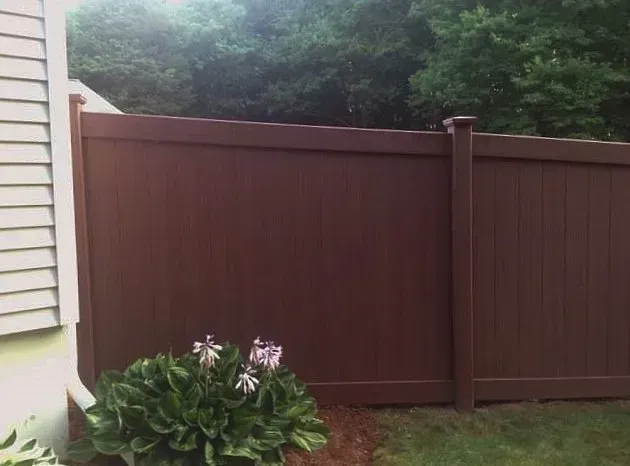 A brown fence with a white house in the background
