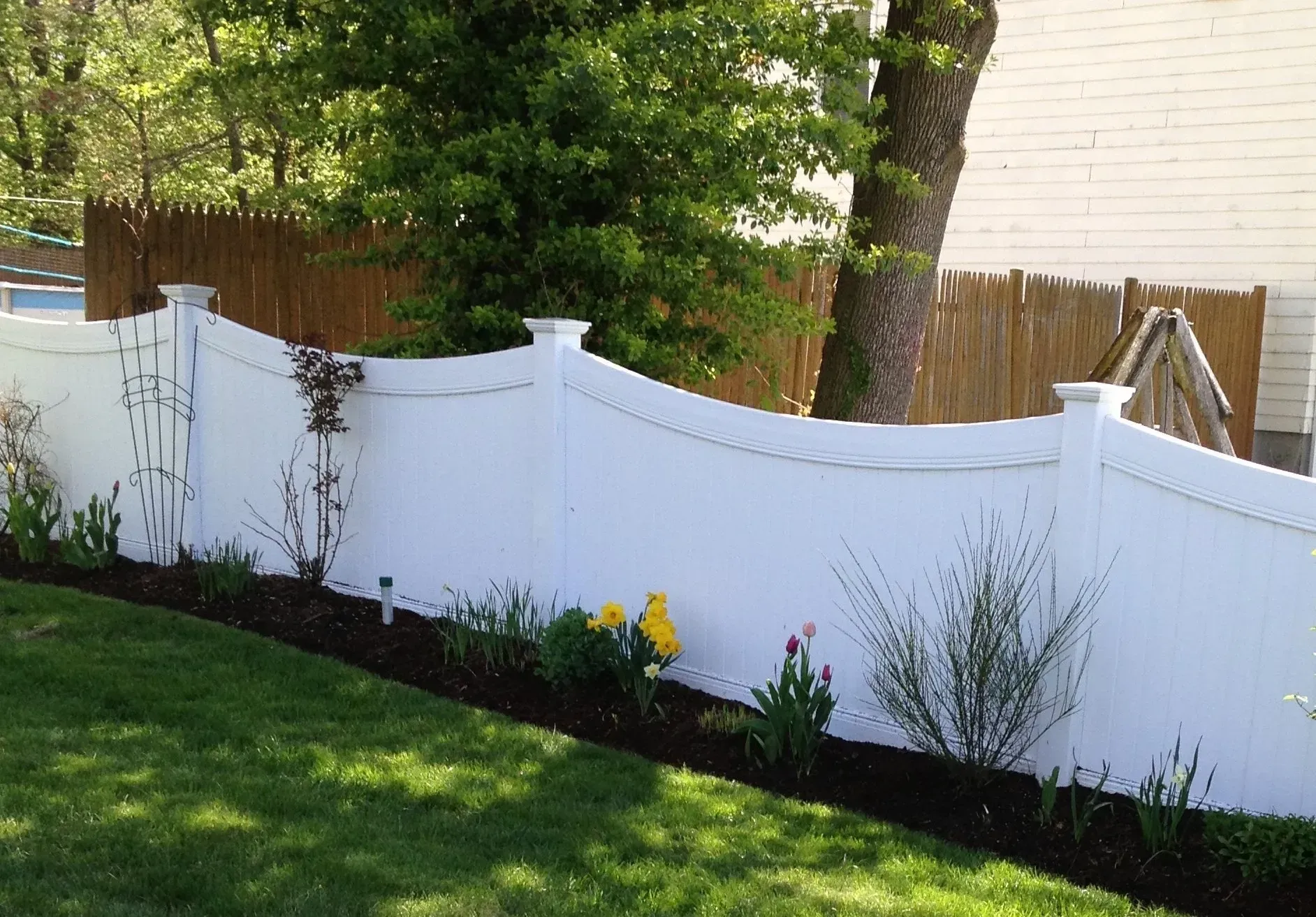 A white fence surrounds a lush green yard