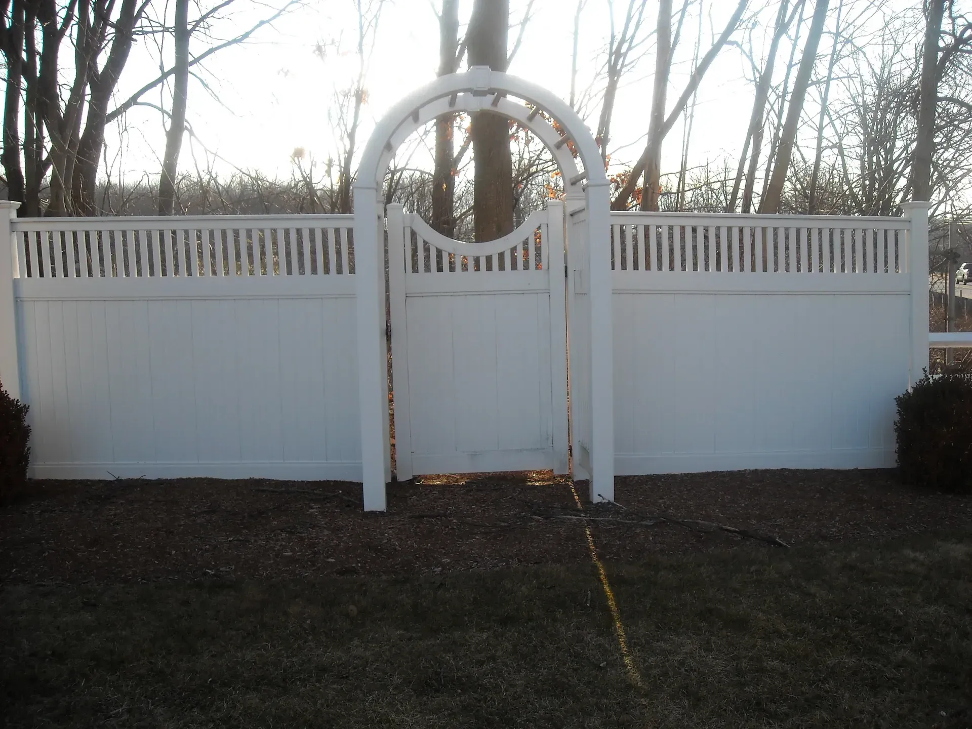 A white fence with a gate in the middle of it