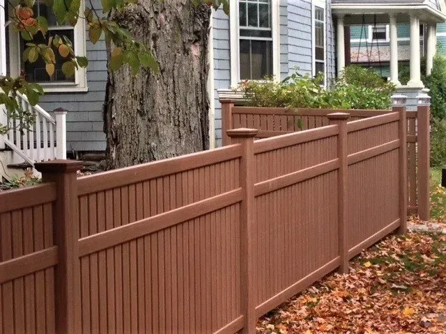 A brown wooden fence is in front of a house