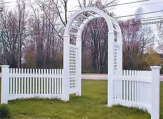 A white picket fence with an archway in the middle of it.