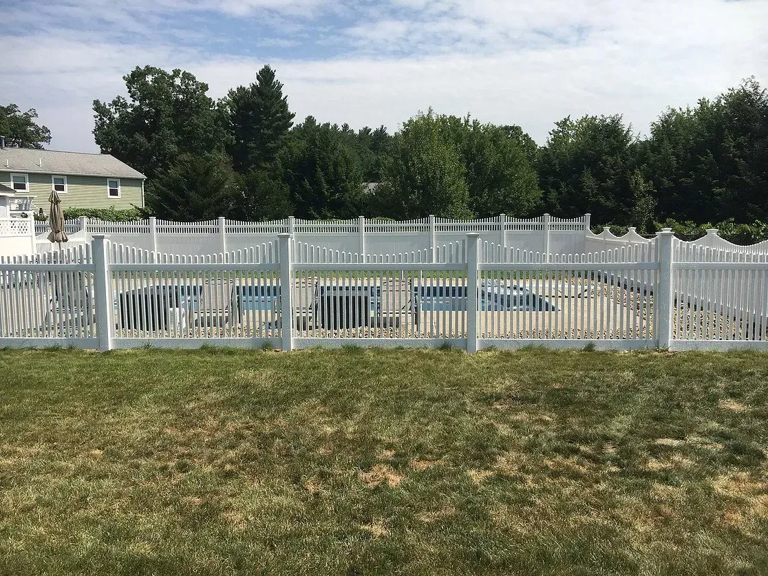 A white fence surrounds a swimming pool in a backyard.