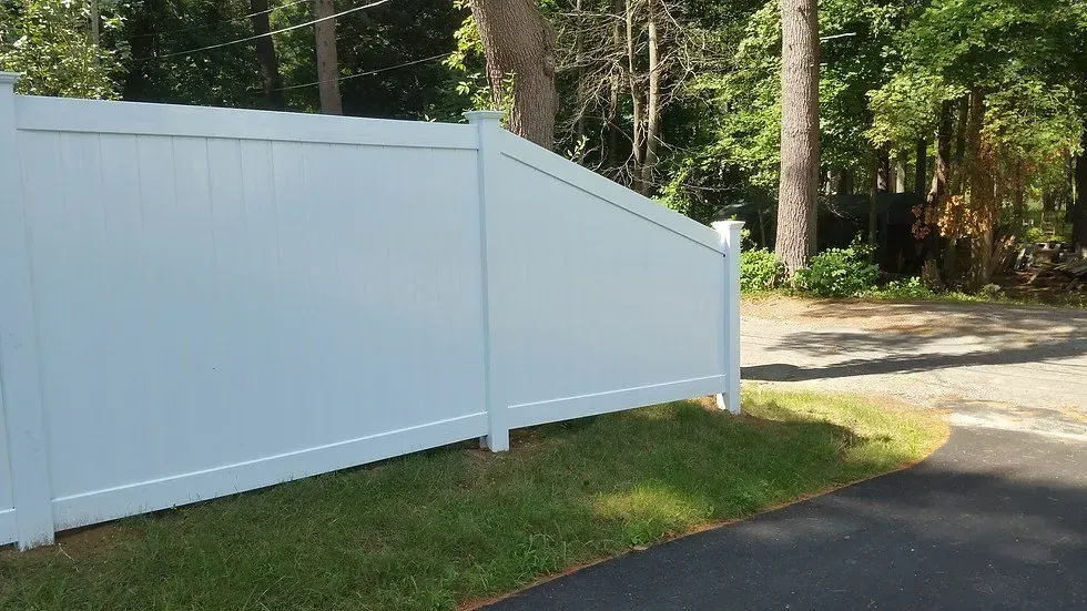 A white fence is sitting in the grass next to a road.