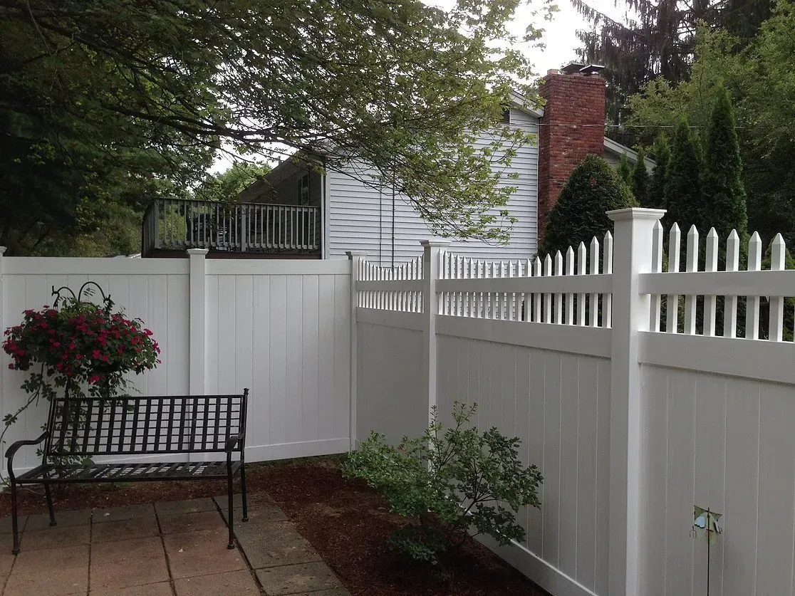 A white fence with a bench in front of it