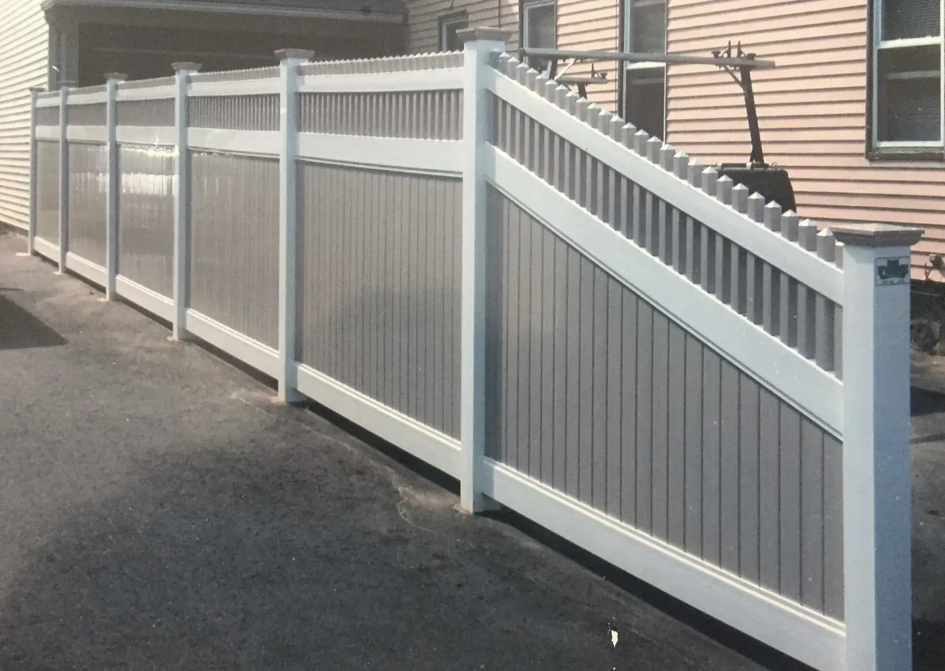 A gray and white fence along the side of a house