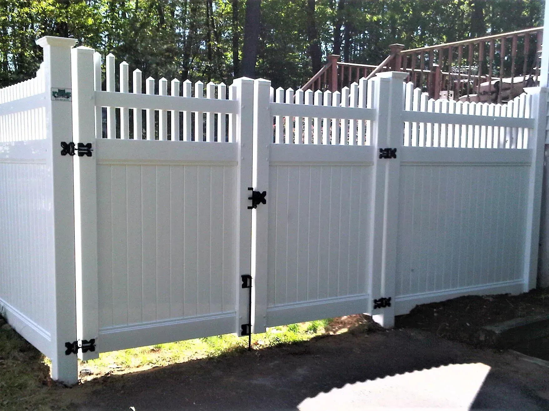 A white fence with a gate and a deck in the background