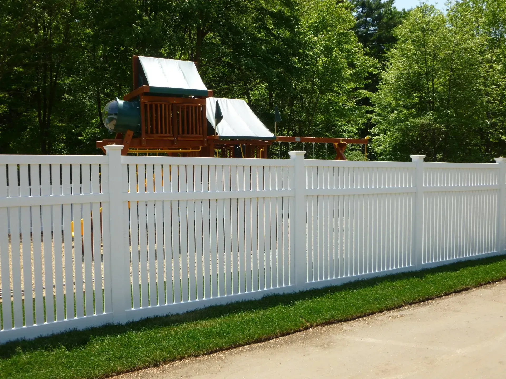A white picket fence with a playground in the background