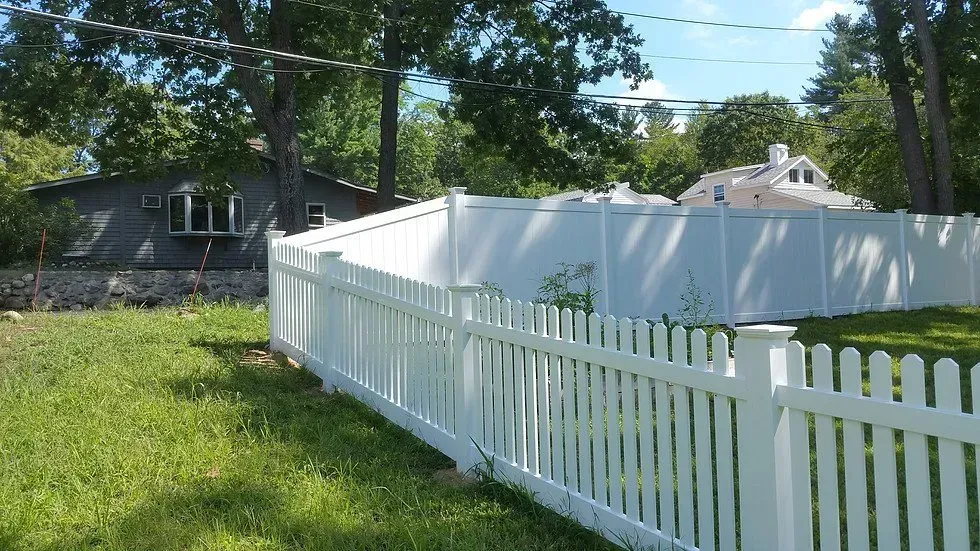 A white picket fence with a house in the background