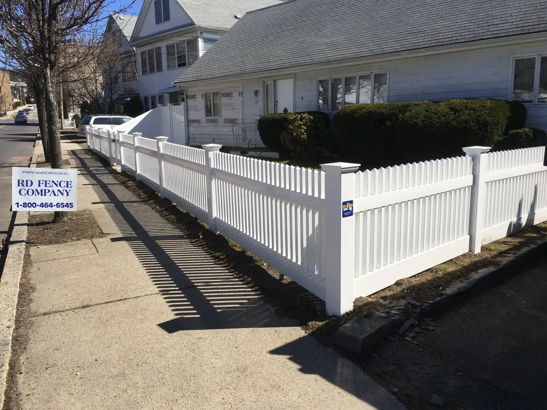 A white picket fence is in front of a house