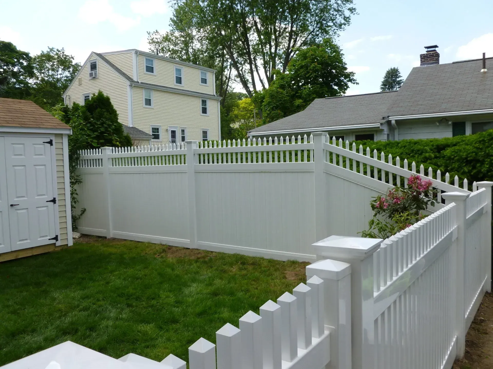 A white picket fence surrounds a lush green yard