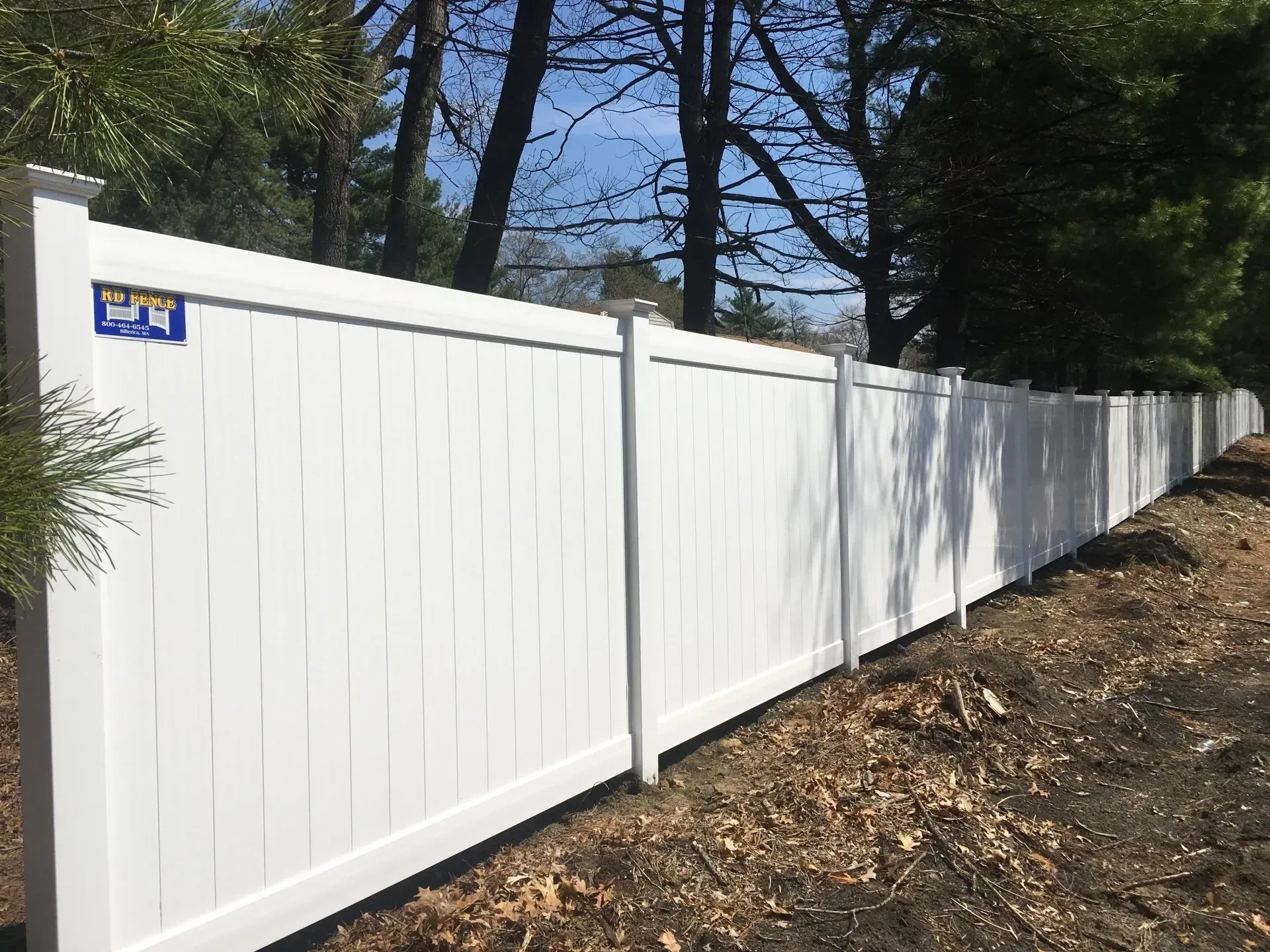 A white vinyl fence is sitting on top of a dirt hill.