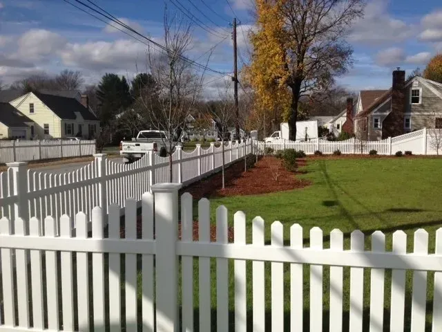 A white picket fence surrounds a lush green yard