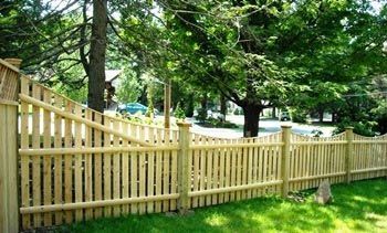 A wooden picket fence surrounds a lush green yard.