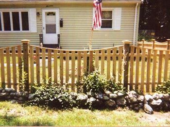 A wooden picket fence is in front of a house
