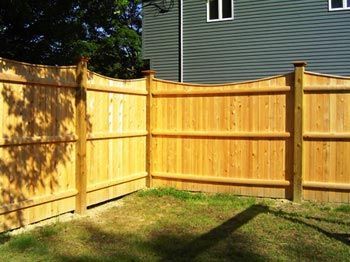 A wooden fence in a backyard with a house in the background.