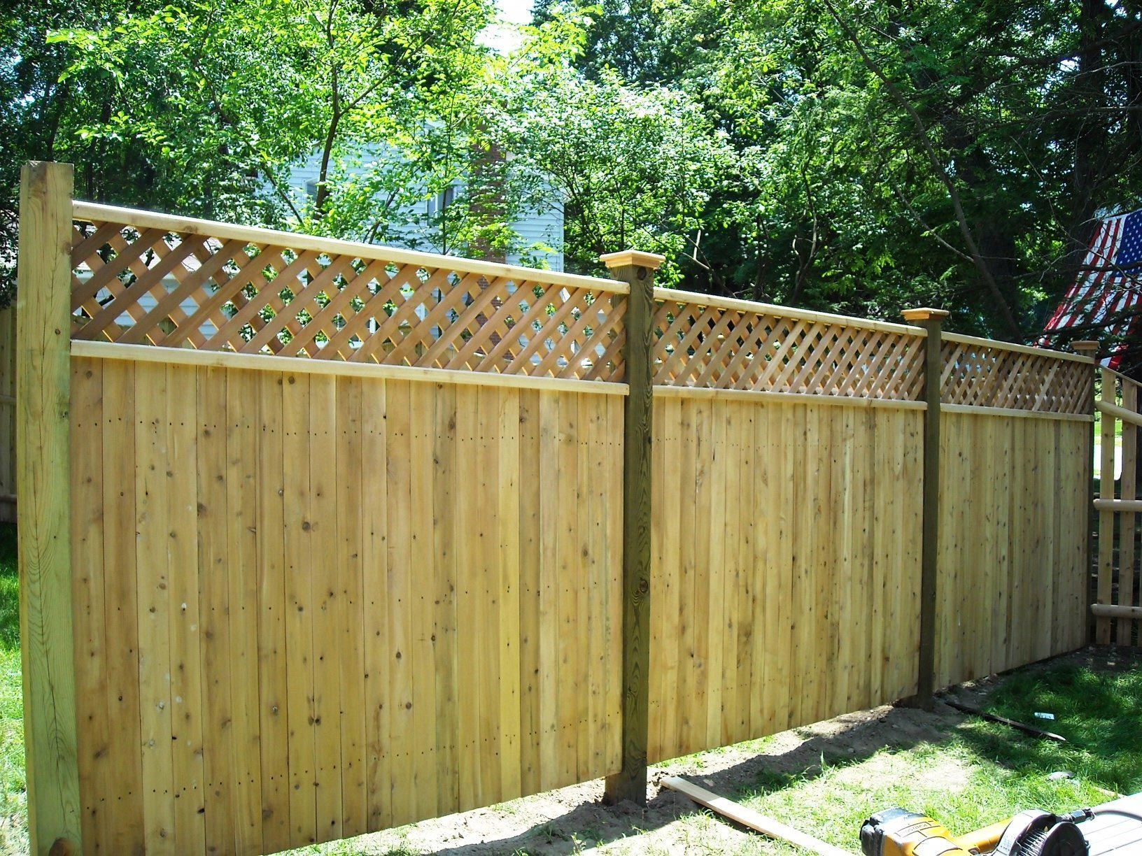 A wooden fence with a lattice top is being built