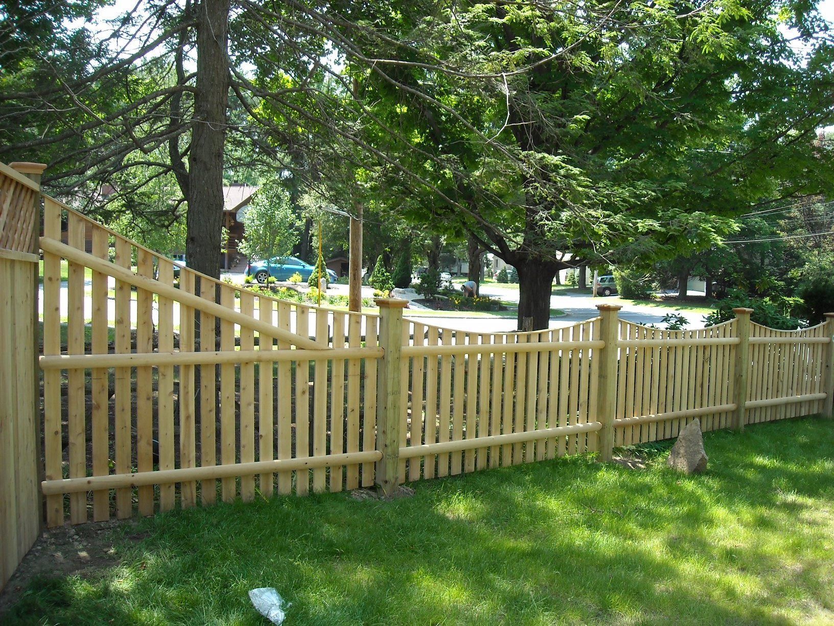 A wooden picket fence surrounds a lush green yard