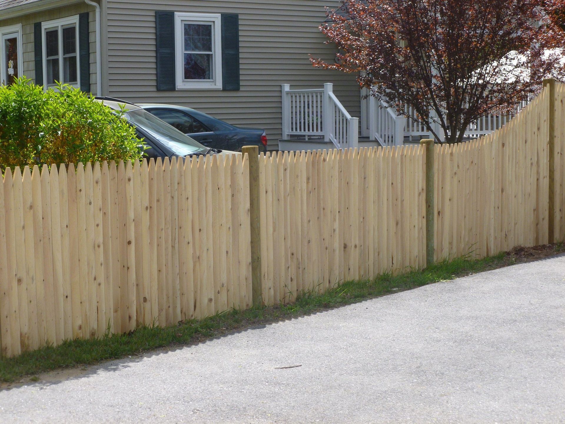 A wooden fence surrounds a driveway in front of a house