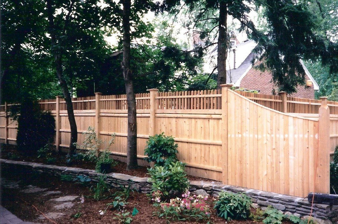 A wooden fence with a stone wall in front of a house