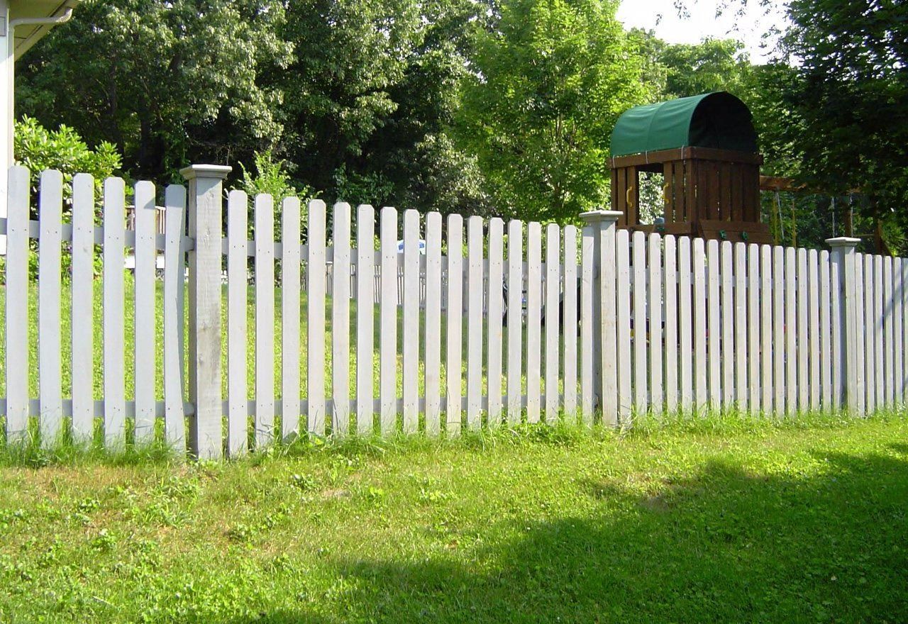 A white picket fence surrounds a lush green yard
