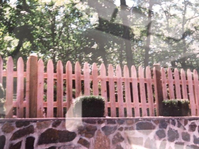 A pink picket fence surrounds a stone wall