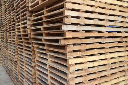 Stacks of wooden pallets in a warehouse, viewed from the side