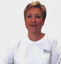 Woman with short blonde hair smiles, wearing a white t-shirt.