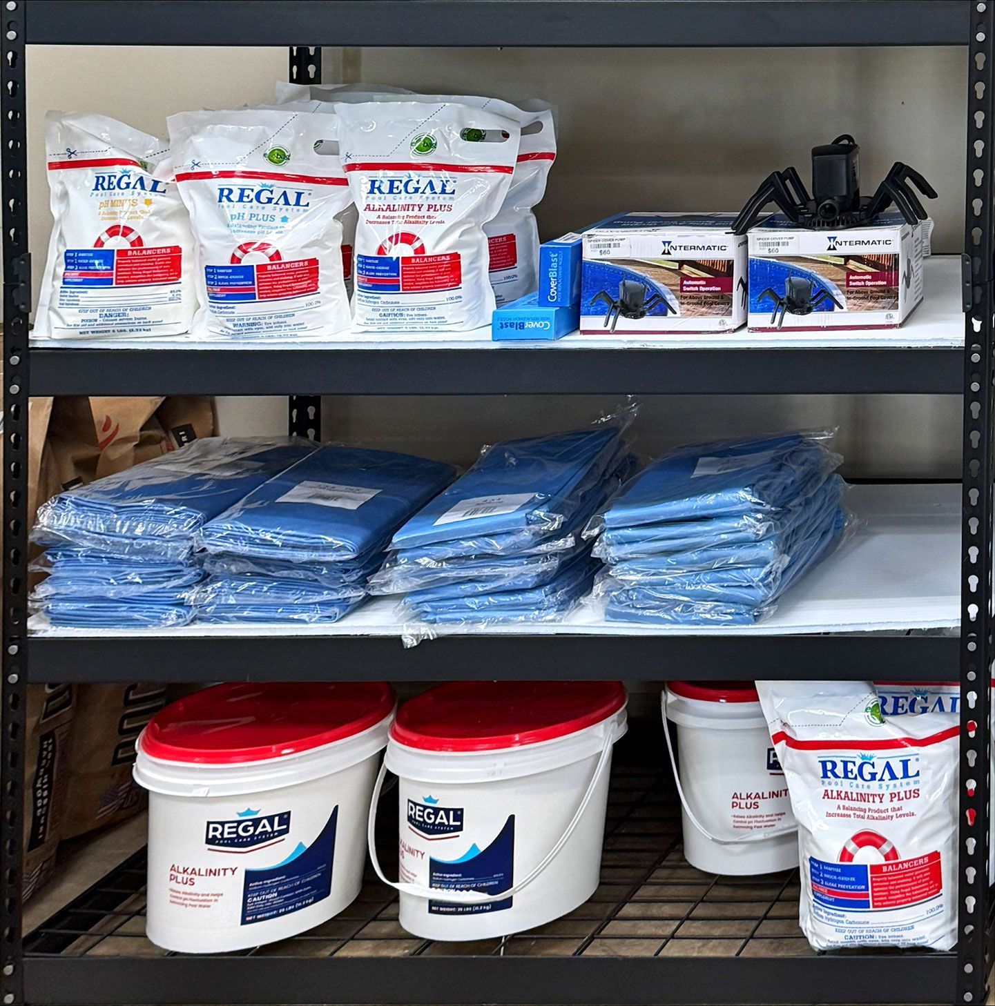 Black metal shelving unit stocked with Regal brand items, including bags, buckets, and blue covers.